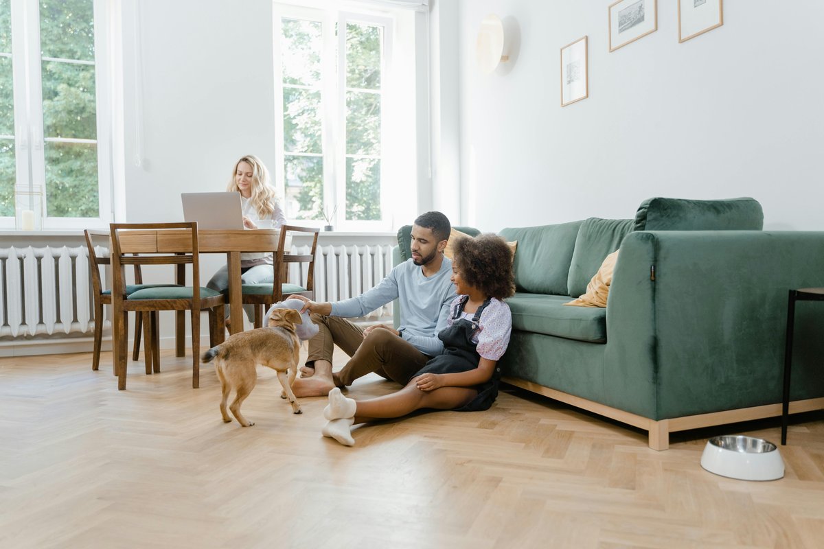 Happy family playing with their dog at home — All Pet Cards helps pet owners afford the best care